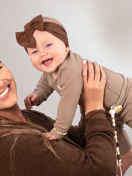 Happy baby and mom wearing matching beaded bracelet in gold, white and beige stainless steel beads 